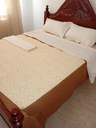 a bed with a wooden headboard and white sheets at Lakeside Beach Hotel in Madwa