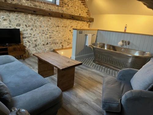 Una sala de estar con una bañera, un sofá y una mesa. en The Ostrich Inn, South Creake, Norfolk, en South Creake