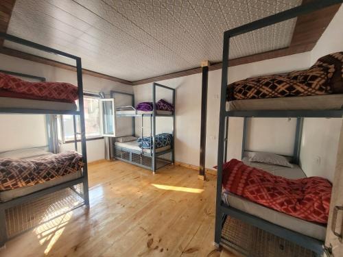 a room with four bunk beds and a wooden floor at DHARAMSHALA inn MUNSYARI in Munsyari