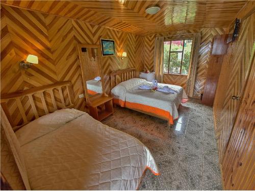 a bedroom with two beds in a wooden room at Hotel Don Taco in Monteverde Costa Rica