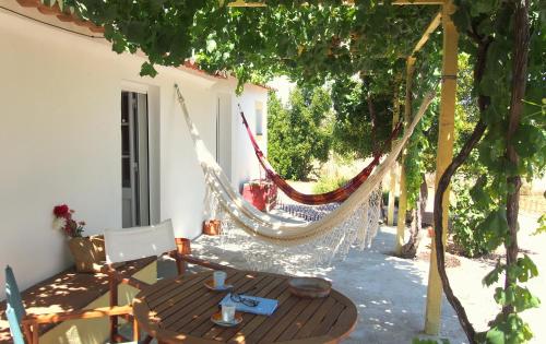 a patio with a hammock and a table and chairs at Monte dos Freixos Country House in São Lourenço de Mamporcão