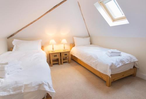 two twin beds in a room with a window at The Stables at Boreham House in Herstmonceux