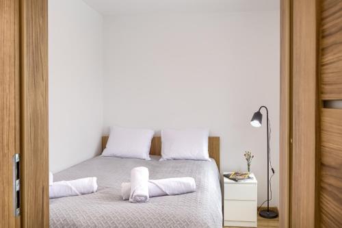 a bedroom with a bed with white sheets and pillows at Apartamenty Słoneczna in Tylicz