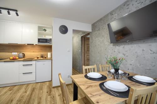 a kitchen and dining room with a wooden table with chairs at Apartamenty Słoneczna in Tylicz