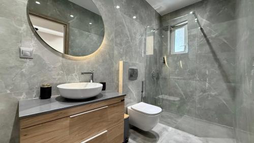 ein Badezimmer mit Waschbecken, Toilette und Spiegel in der Unterkunft SKY 5 Luxury Apartment in Kalamata