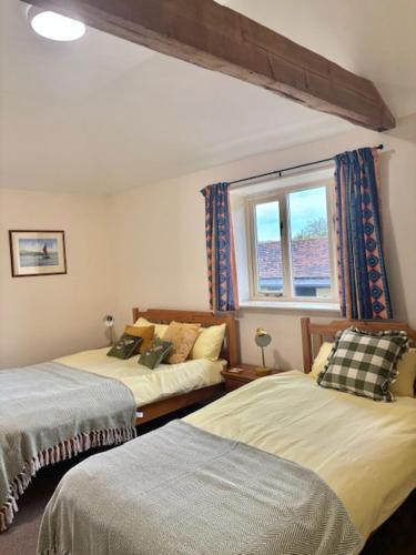 a bedroom with two beds and a window at The Farmyard at Doddington in Doddington