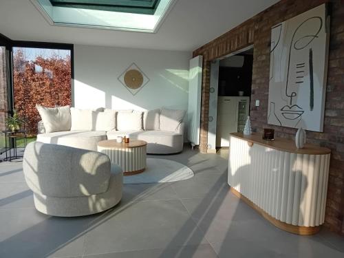 un soggiorno con 2 divani bianchi e 2 tavoli di LE CLOS DU MONTYS a Louveigné