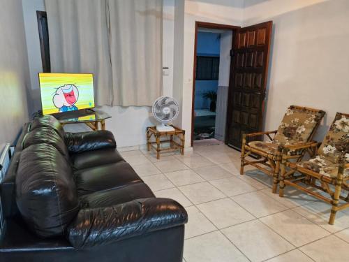 een woonkamer met een leren bank en 2 stoelen bij Condomínio Dell Mar in Bertioga