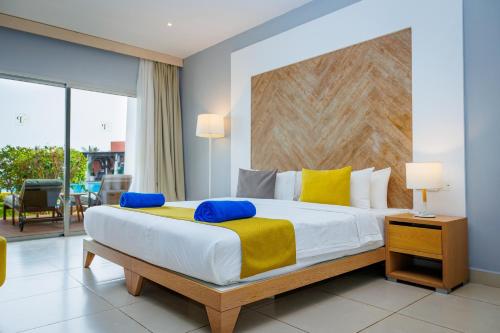 a bedroom with a large bed with yellow and blue pillows at African Princess Beach Hotel in Serekunda