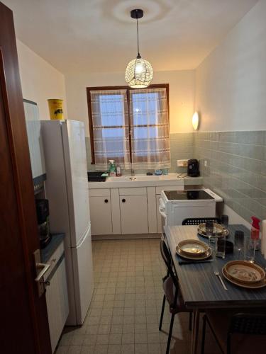a small kitchen with a table and a refrigerator at Appartement 70m2 en résidence calme avec terrasse in Avallon