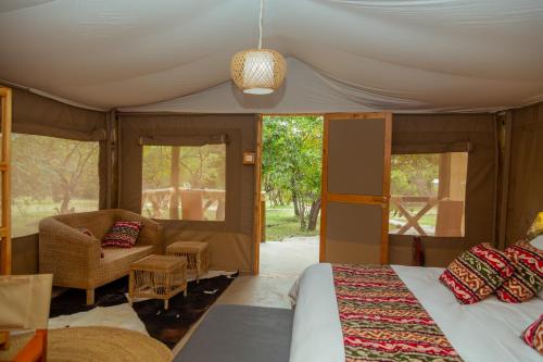 a bedroom with a bed and a couch and a chair at Kipekee Zuri Camp in Ololaimutiek