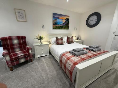 a bedroom with a bed and a chair and a clock at Little Spinney Lodge in Saint Leonards