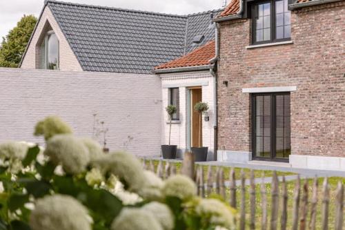 een stenen huis met een hek ervoor bij Villa - The Cozy Relax Home - Comfort Nature & Style in Beernem