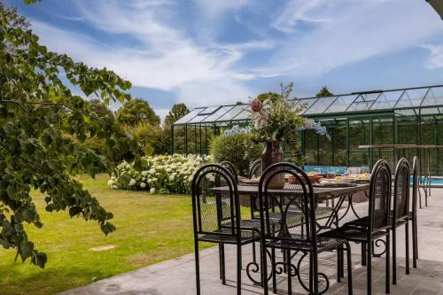 een tafel en stoelen in een tuin met een kas bij Villa - The Cozy Relax Home - Comfort Nature & Style in Beernem