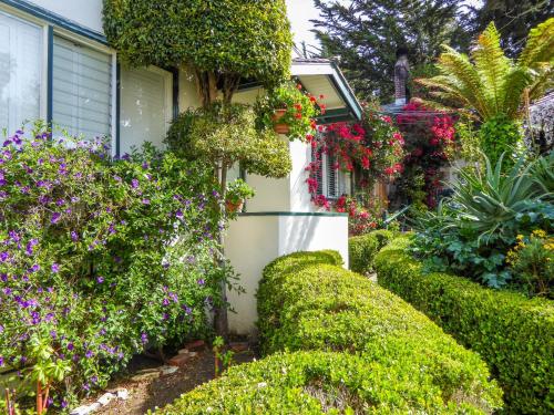 a garden with flowers and bushes next to a house at Carmel Fireplace Inn in Carmel