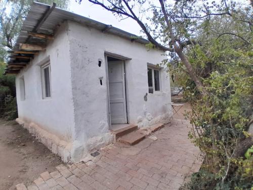 een klein wit huisje met een deur op een bakstenen binnenplaats bij Monoambiente Magia Uritorco in Capilla del Monte