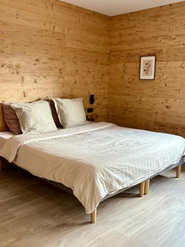 a large bed in a room with wooden walls at Chalet Lilas, spa privatif, 2p in Rochesson