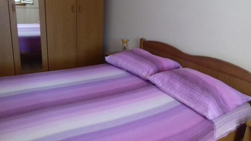 a bed with purple sheets on top of it at Apartments Gugic in Prigradica