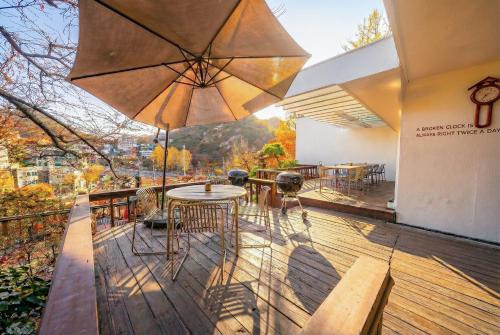 eine Holzterrasse mit Tisch und Sonnenschirm in der Unterkunft BS Urban Retreat Garden and Spa near Gyeongbokgung in Seoul
