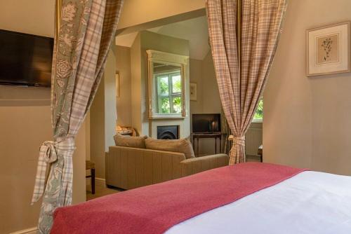 a bedroom with a bed and a couch and a window at The Five Arrows Hotel in Waddesdon