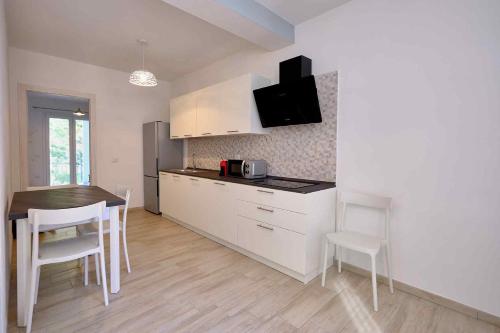 une cuisine avec des armoires blanches et une table et des chaises dans l'établissement Le Magie di Gioba, à Chia