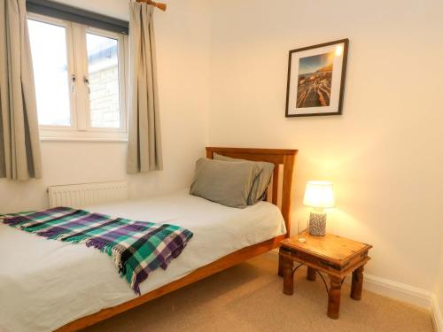 a bedroom with a bed and a table and a window at Ash Corner Cottage in Weymouth