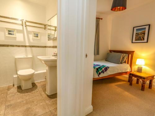 a bathroom with a bed and a toilet and a sink at Ash Corner Cottage in Weymouth