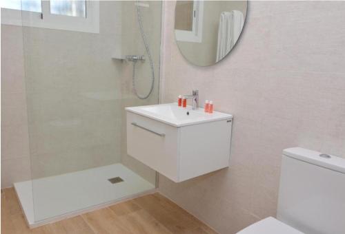 un bagno bianco con lavandino e specchio di Apartamentos Odysea By Apartamentos Valentia a Cala de Finestrat