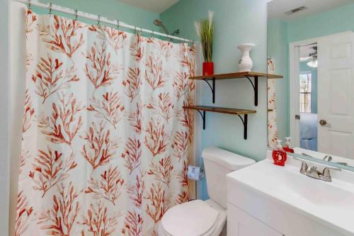 a bathroom with a white toilet and a shower curtain at Paradise in the Palms in Mexico Beach