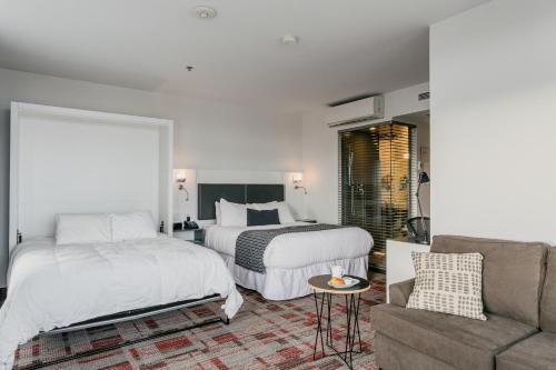 a hotel room with two beds and a couch at Riotel Matane in Matane