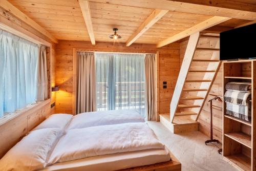 Un dormitorio con una cama y una ventana grande. en Noah Suites, en Vigo di Fassa