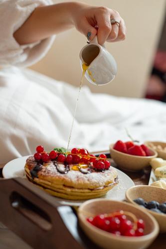 a person pouring syrup onto a cake with fruit on it at Hotel Belvedere in Predeal
