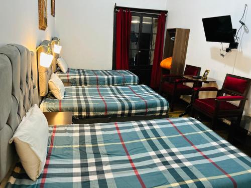 Una sala de estar con dos camas y una silla. en Hotel el Conquistador, en Cusco