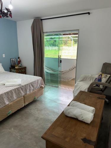 a bedroom with a bed and a table and a window at Pousada Villa Felicidade in Guarapari