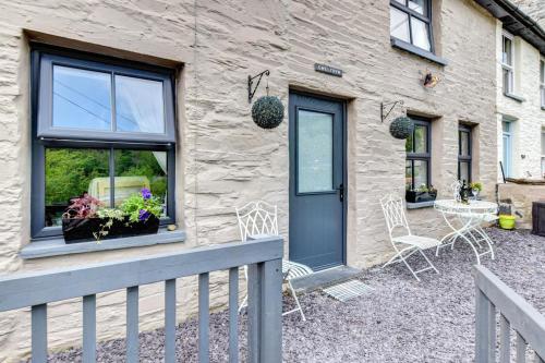 een stenen huis met een blauwe deur en stoelen bij 3 Bed in Machynlleth oc-bow43 in Corris