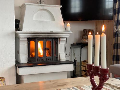 a fireplace with three white candles on a table at Nostalgic Cabin With 3 Br, Fireplace, And Terrace in Beitostøl
