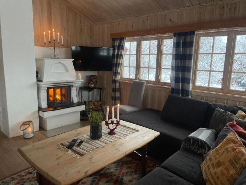 a living room with a couch and a table with a fireplace at Nostalgic Cabin With 3 Br, Fireplace, And Terrace in Beitostøl