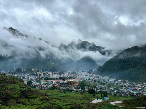 a town in the middle of a valley with mountains at Thào Gia Homestay Mèo Vạc in Ha Giang