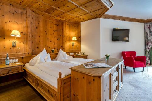 sypialnia z dużym łóżkiem i czerwonym krzesłem w obiekcie Hotel Post Lermoos superior w mieście Lermoos