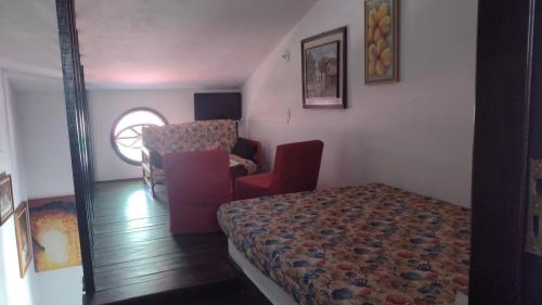 a room with a bed and a chair in it at Condomínio Vila Gustavo excelente localização in Caraguatatuba