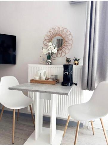 a dining room table with white chairs and a mirror at Central Studio - Proche Bâle & St Louis in Saint-Louis