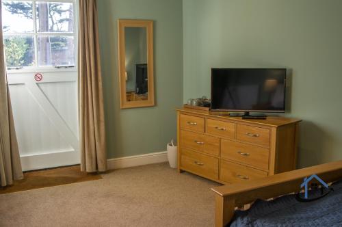 een slaapkamer met een televisie op een dressoir met een spiegel bij Coach House at The George Pub, Ashley, Market Harborough in Ashley