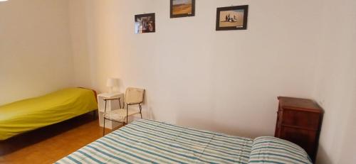 um quarto com uma cama, uma cadeira e quadros na parede em Blu Mare em Punta Marina