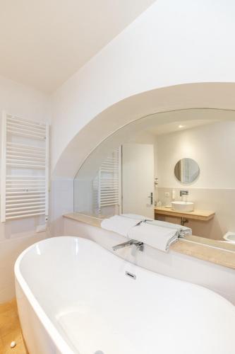 a white bathroom with a tub and a mirror at Giotto Hotel & Spa in Assisi