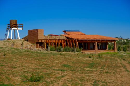 a house on a hill with a windmill in the background at Rancho El Rossinyol in Valle de Guadalupe