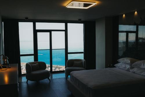 a bedroom with a bed and two chairs in front of windows at Şahin Tepesi Suites I Rize in Rize