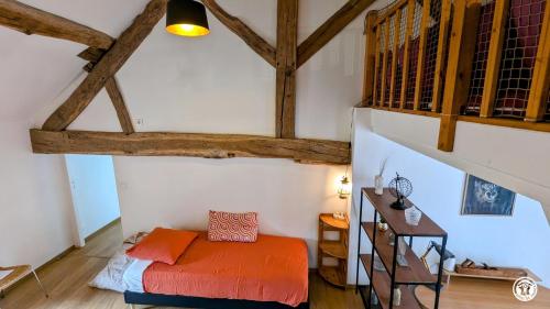 ein Schlafzimmer mit einem orangenen Bett in einem Zimmer mit Holzdecken in der Unterkunft Ô Coeur des Liens in Saint-Seine-lʼAbbaye