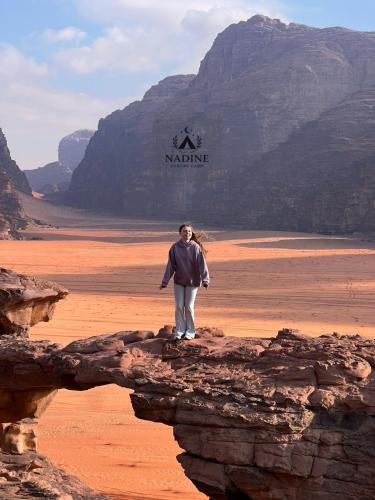 een vrouw op een rots in de woestijn bij Nadine Luxury Camp in Wadi Rum