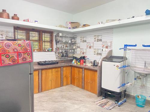 Una cocina con gabinetes de madera y refrigerador. en Casa 2bhk home, en Parxem