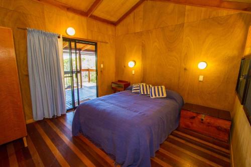 a bedroom with a bed in a room with wooden floors at Bimbimbi in Seventeen Seventy